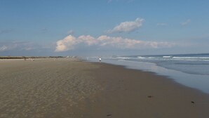 A wide sandy beach with gentle waves, a clear sky, and a few people in the distance. - The Falls at Ogunquit Resort, Maine (Ogunquit)
