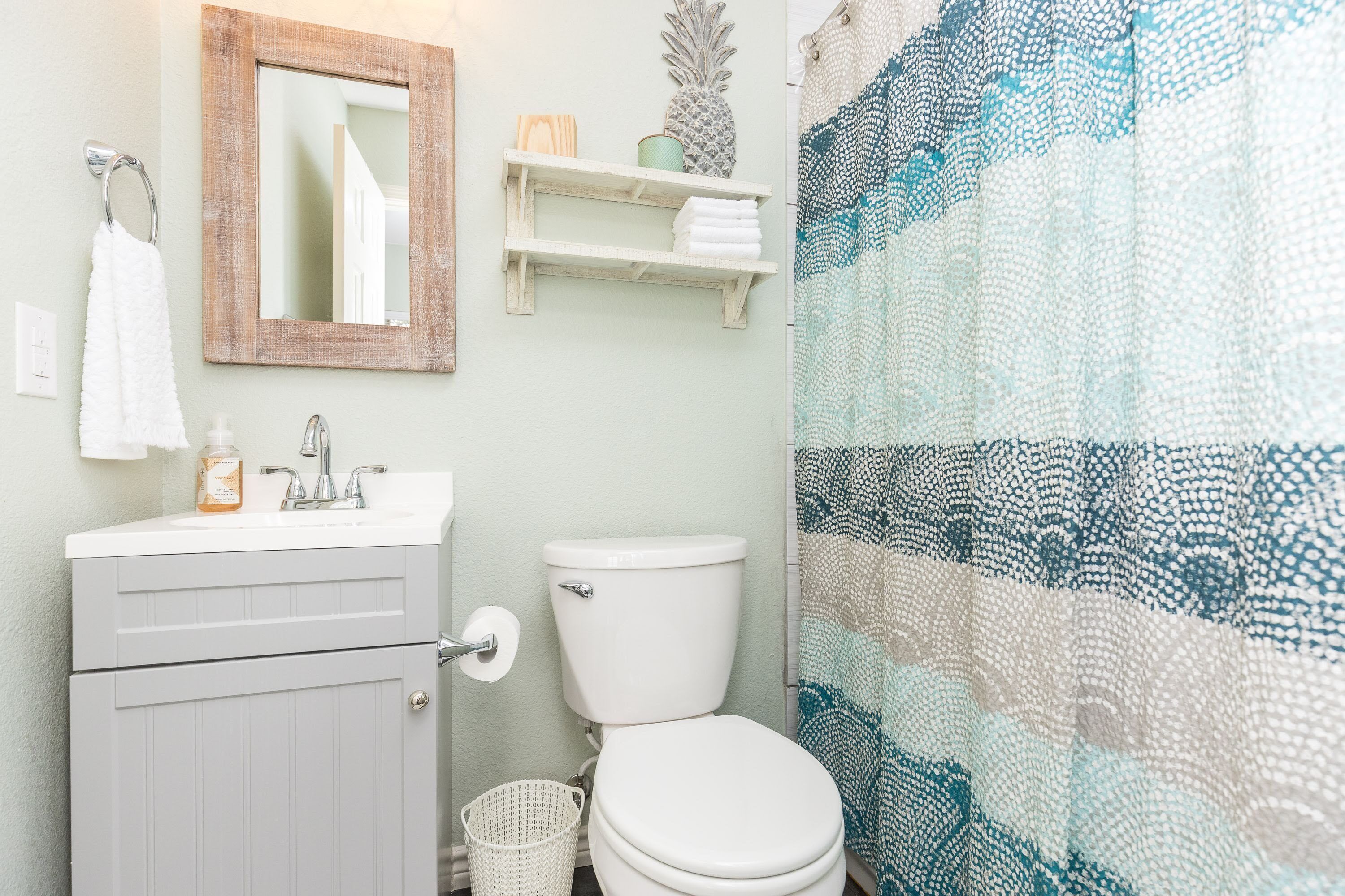 A bathroom with a white sink, a toilet, a mirror, and a shower curtain.