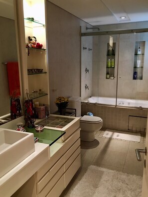 Een bad/douchecombinatie, een bubbelbad, een haardroger, handdoeken