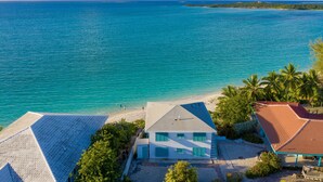 A coastal property with a beach, a white building with blue shutters, and a red-roofed structure. - Driftwood First Floor Condo at Hoopers Bay With Stunning Views (Georgetown)