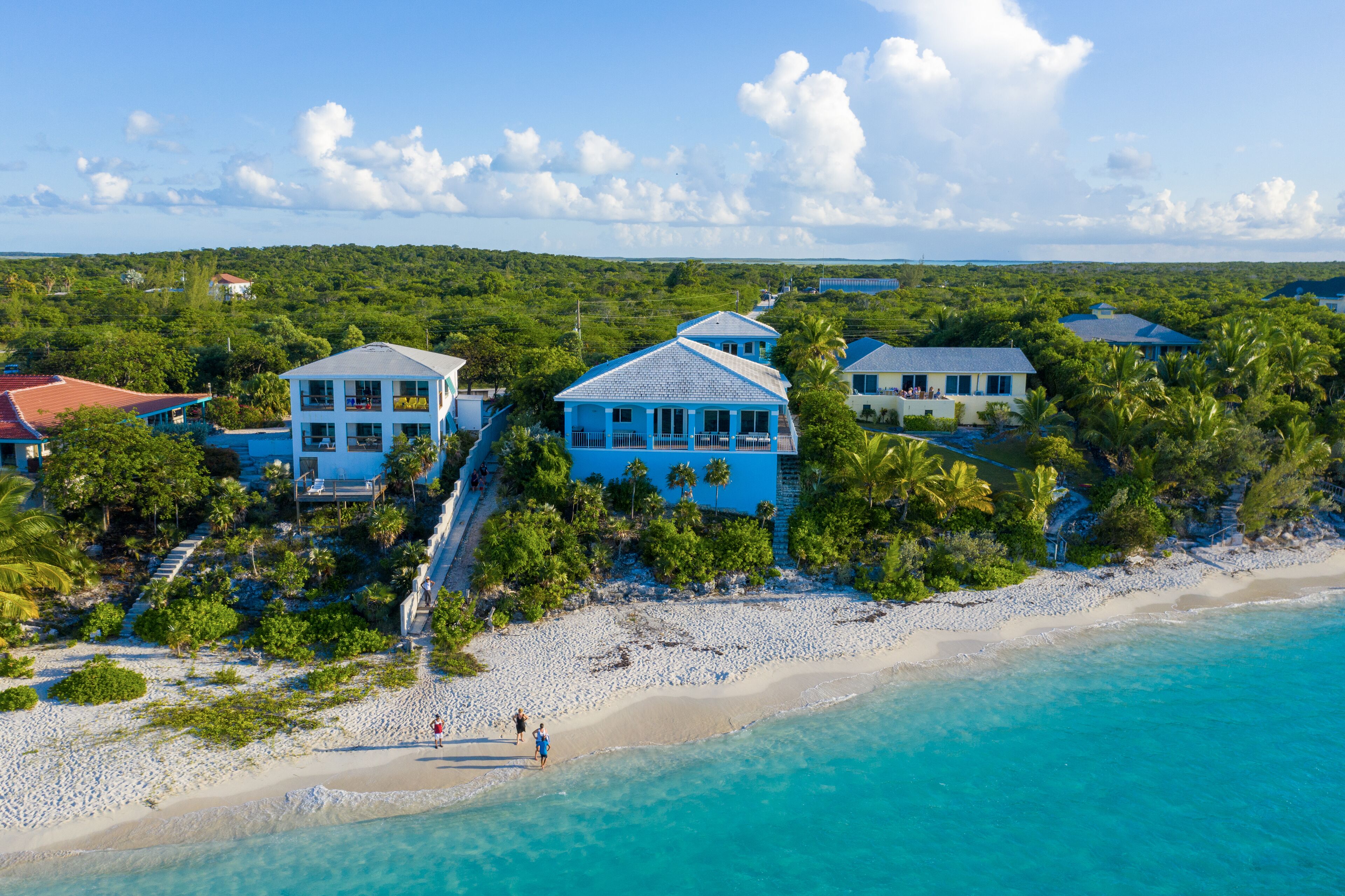 A coastal property with multiple buildings, a beach, and clear turquoise waters.
