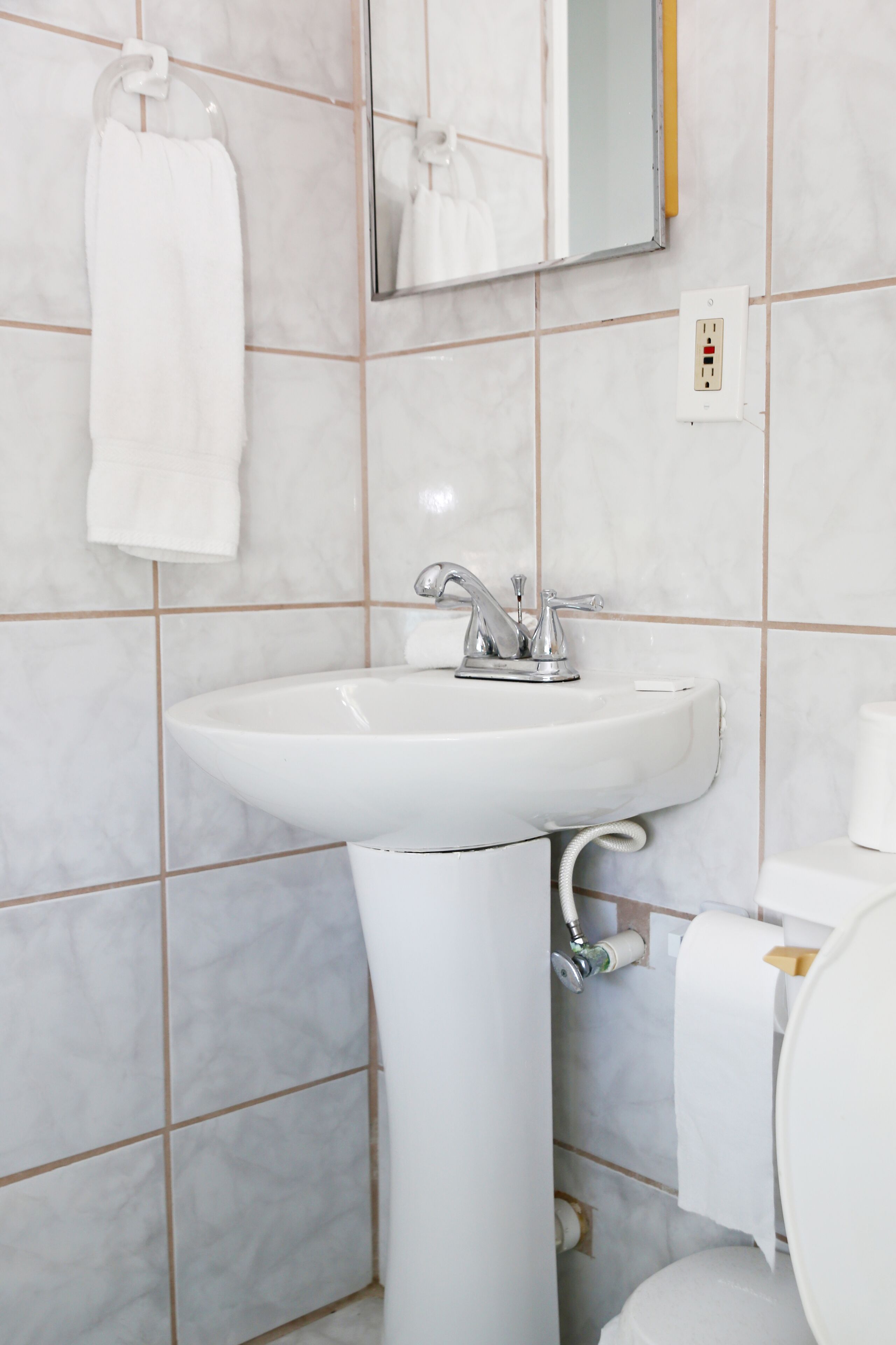 A bathroom with a white sink, mirror, and toilet.