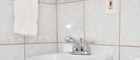 A bathroom with a white sink, mirror, and toilet.