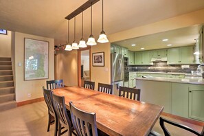 A dining area with a wooden table and chairs, a map on the wall, and a kitchen in the background. - North Lake Tahoe Cabin: 4 Mi to the Beach! (Tahoe Vista)