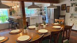 A dining area with a wooden table set for six, surrounded by chairs.