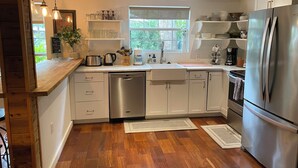 A modern kitchen with white cabinets, stainless steel appliances, and wooden flooring.
