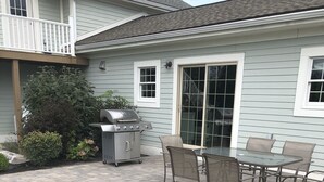 A patio with a grill and chairs.