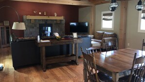A spacious living area with a fireplace, a television, a dining table with chairs, and a stone accent wall.