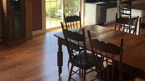 A spacious kitchen with wooden cabinets, a large dining table, and a view of a wooden deck.