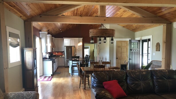 A spacious living area with a leather sofa, a dining table, and a kitchen in the background.