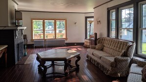 Um quarto espaçoso com uma grande janela, lareira, sofá e mesa.