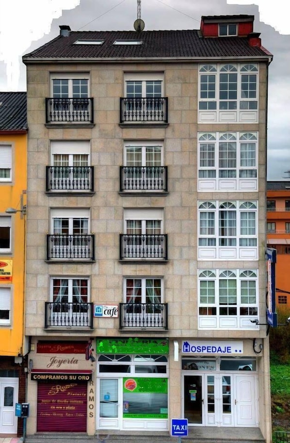 Un edificio de varios pisos con una cafetería, una farmacia y un negocio en la planta baja.