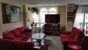A living room with red sofas, a TV, and a bookshelf.