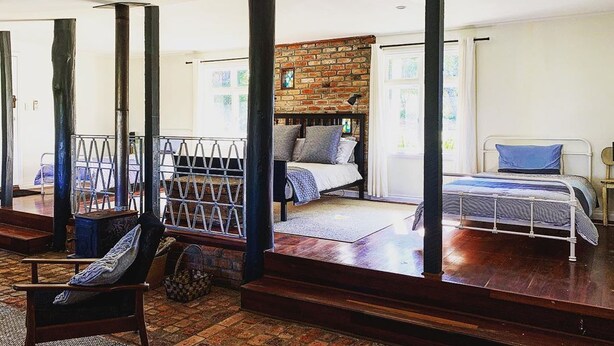 Un dormitorio con pared de ladrillo, una cama con cabecera y una ventana.