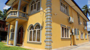 A two-story house with a balcony, large windows, and an air conditioning unit.