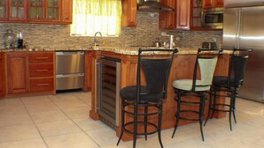 A kitchen with wooden cabinets, a stainless steel refrigerator, and a granite countertop.