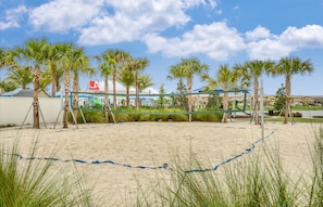 Une plage de sable avec des palmiers et un filet de volley-ball.