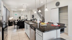 A modern kitchen with a central island, stainless steel appliances, and pendant lighting. - Stunning 5bd Retreat, Pool, BBQ, PS5 & Game Room, Jnear Disney (Kissimmee)