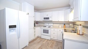 A kitchen with white cabinets, a built-in microwave, a stove, and a refrigerator. - Holiday Cottage-Oceanside 77th St, W/D, AC, Free WIFI (Ocean City)