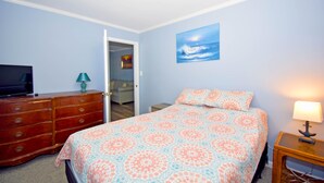 A bedroom with a bed, dresser, TV, and artwork on the wall. - Holiday Cottage-Oceanside 77th St, W/D, AC, Free WIFI (Ocean City)