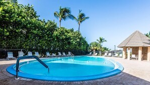 En swimmingpool med solstolar och en pergola.