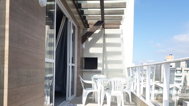 Een balkon met een tafel en stoelen, een schuifdeur en uitzicht op de stad.