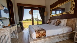 Une chambre avec un grand lit, une tête de lit en bois et une vue sur un champ.