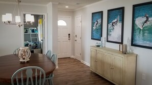A dining area with a wooden table and chairs, a chandelier, and a cabinet with artwork.