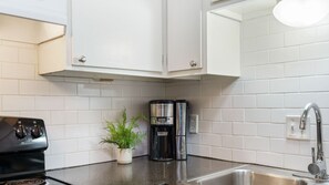 A kitchen with white cabinets, a black stove, a coffee maker, and a sink. - Central Austin 2 Story Apt | Sleeps 4 + Free Prkg (Austin)