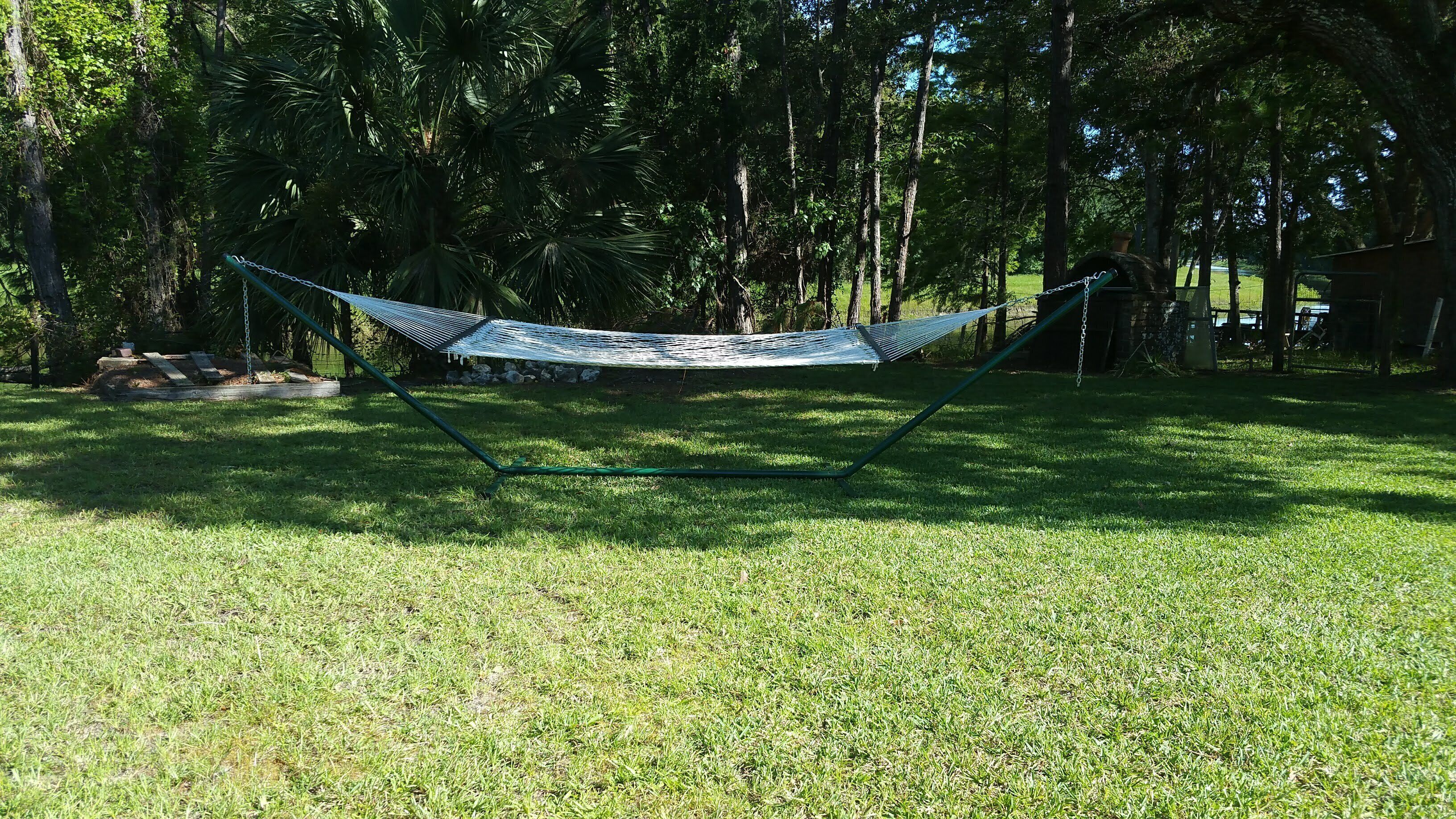A hammock set up in a grassy area with trees in the background.
