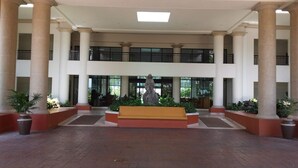 A spacious lobby with a central bench, columns, and potted plants.