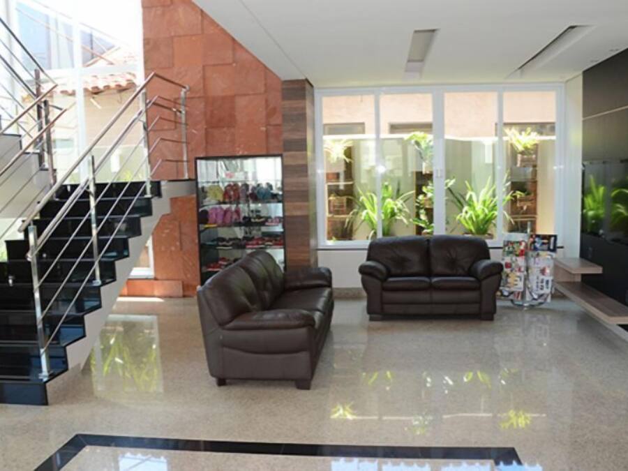 A modern living room with a staircase, leather sofas, and a glass display case.