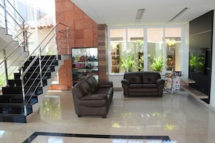 Uma sala de estar moderna com escada, sofás de couro e uma vitrine de vidro.