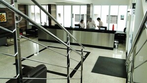A modern reception area with a glass partition, a metal staircase, and a clean, tiled floor. - Nacional Hotel Jataí (Jatai)