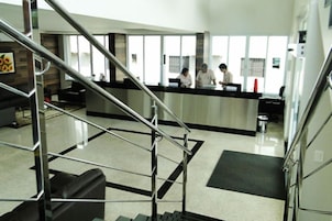 Uma área de recepção moderna com divisória de vidro, escada de metal e piso revestido de azulejos.