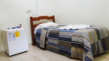 Una habitación pequeña y sencilla con cama, mesita de noche y refrigerador.