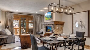 Una sala de estar moderna con chimenea, comedor y un televisor grande montado en la pared.
