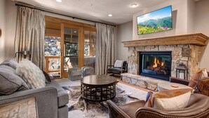 Una sala de estar acogedora con chimenea, asientos cómodos y un televisor grande montado en la pared.