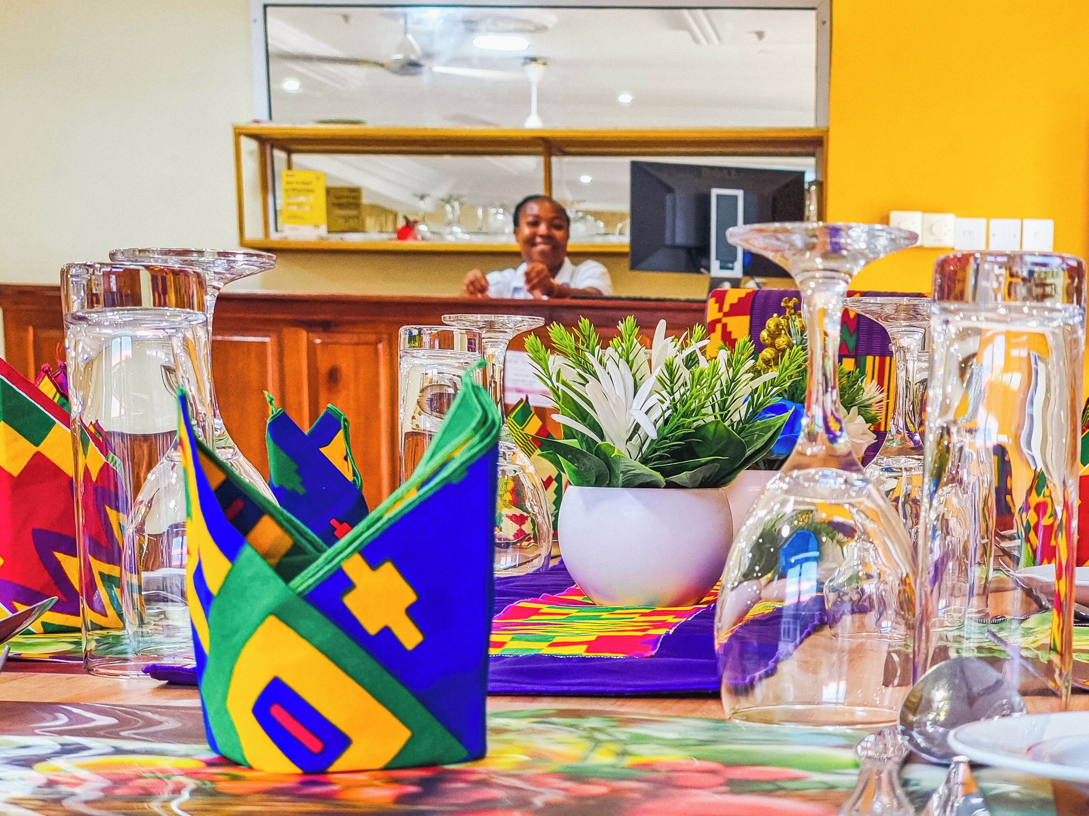 Una habitación de hotel con una mesa de comedor cubierta con manteles de colores y cristalería.