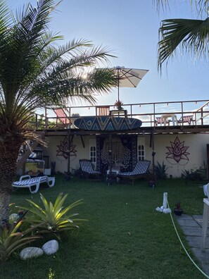 A patio area with lounge chairs, a palm tree, and a decorative wall. - HTL Personalizada Buzios (Búzios)