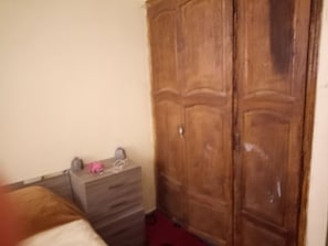 Simple, functional room with a wardrobe and dresser for storage.