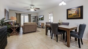 A spacious living room with a ceiling fan, a dining table with chairs, a sofa, and a coffee table. - Sage Suite II - Safe, Cozy & Pet Friendly. (San Antonio)
