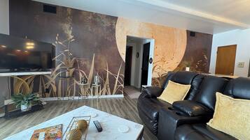 Relax in this stylish living room with a comfortable sofa, flat-screen TV, and a unique wall design.