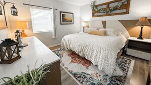 A bedroom with a large bed, bedside tables, a desk, and a window with curtains. - Country Apartment Rental in an Outdoor Paradise! (Mt Carroll)
