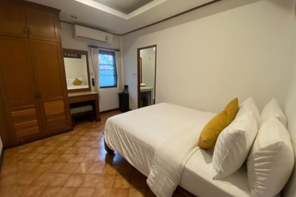 Un dormitorio con cama, armario, espejo y ventana.