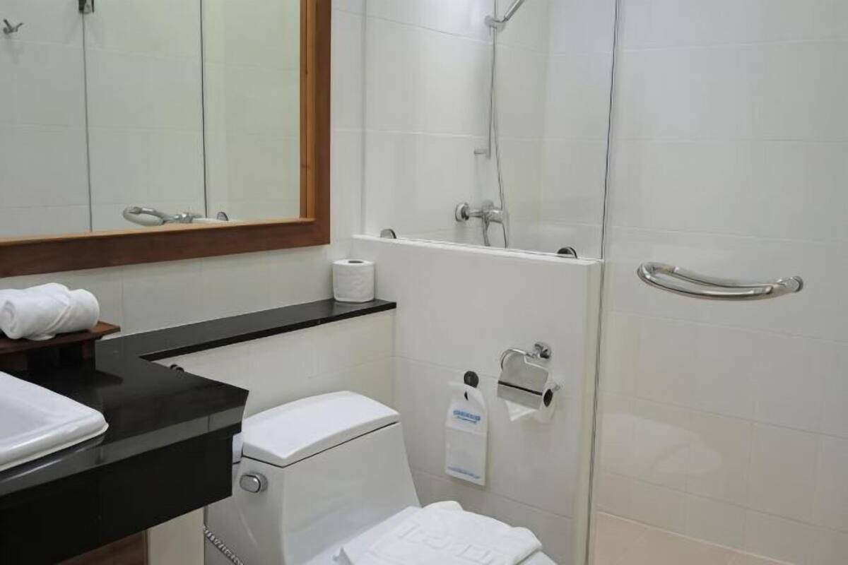 A bathroom with a toilet, a sink, a mirror, a shower, and a towel rack.