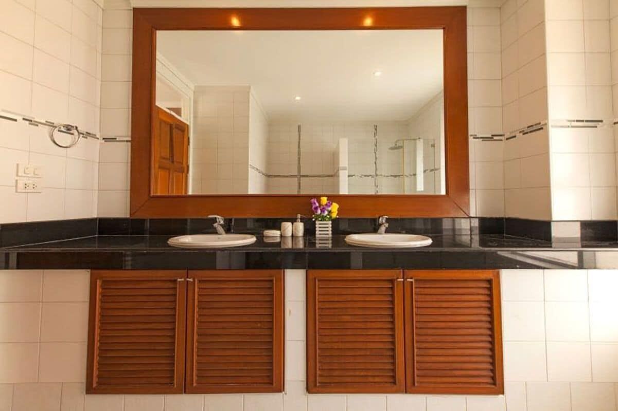 A bathroom with two sinks, a large mirror, and wooden cabinets.