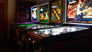 A row of arcade machines with colorful graphics and lights. - A Clean, Safe, House full of steel balls & vintage game consoles (Richmond)