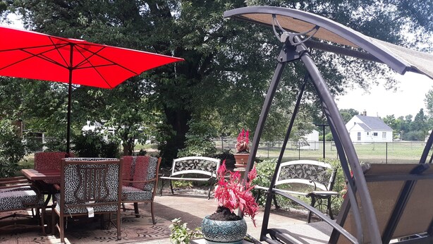 An outdoor patio with a swing chair, a red umbrella, and a table with chairs. - A Clean, Safe, House full of steel balls & vintage game consoles (Richmond)