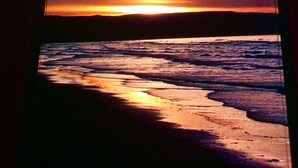 A sunset view through a window with a beach and ocean. - BEACHFRONT STUDIO APARTMENT WITH GREAT VIEW OF THE OCEAN. (Cabarete)